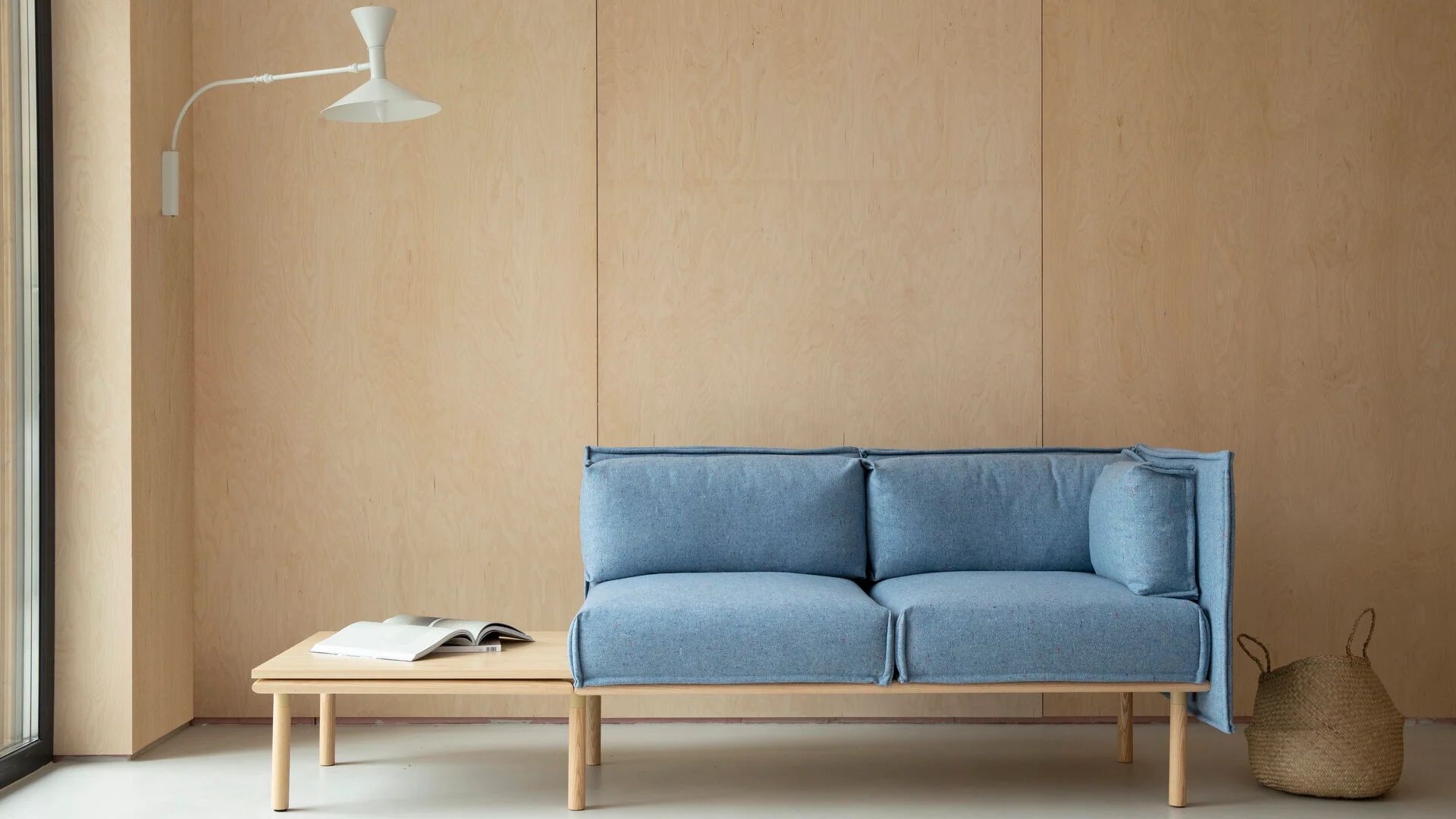 Blue modular sofa with high side panels in a warm wood-lined interior